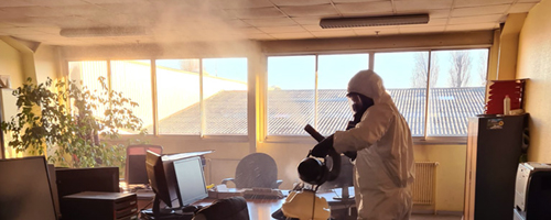 Technicien désinfectant un bureau de la covid-19